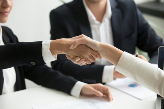 two-people-shaking-hands-in-front-of-a-laptop.jpg two people shaking hands in front of a laptop